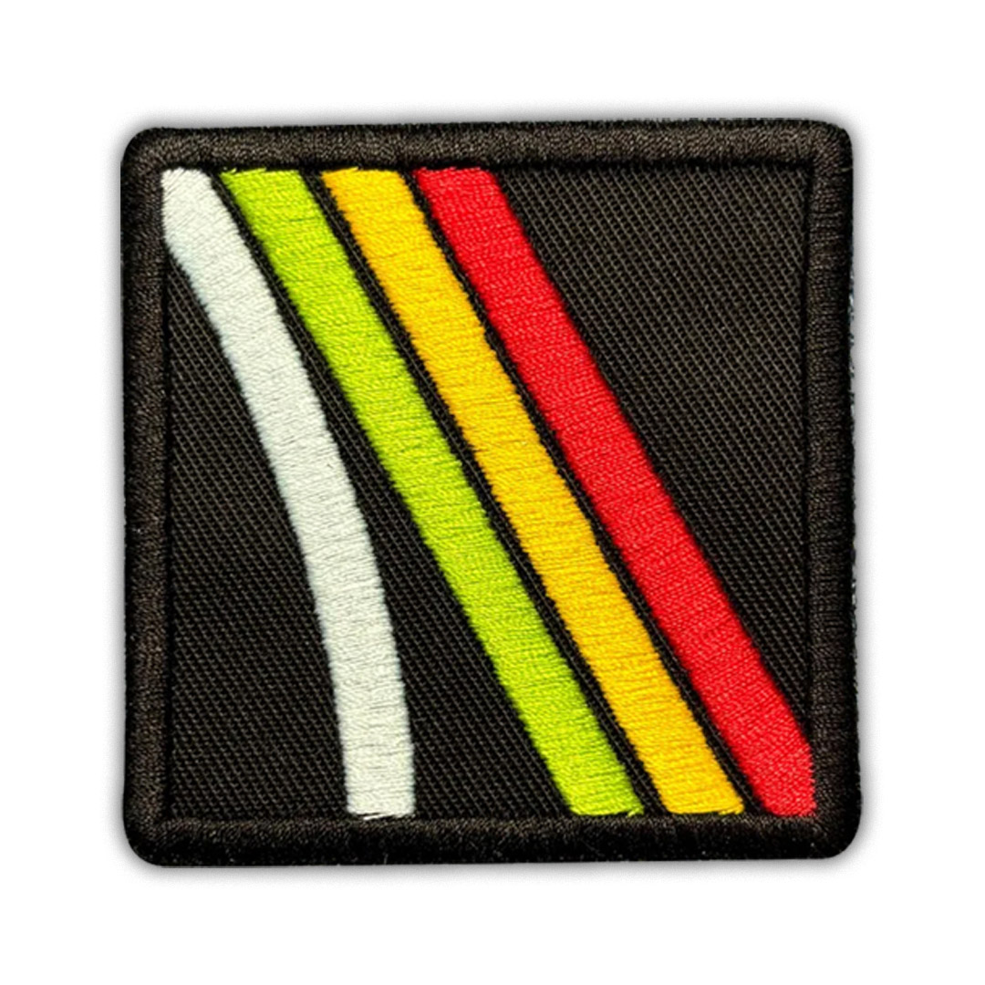 Square black patch with diagonal embroidered stripes in white, green, yellow, and red.