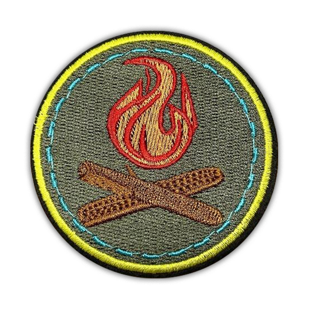 Round olive green scout patch with embroidered red campfire flame and brown logs.