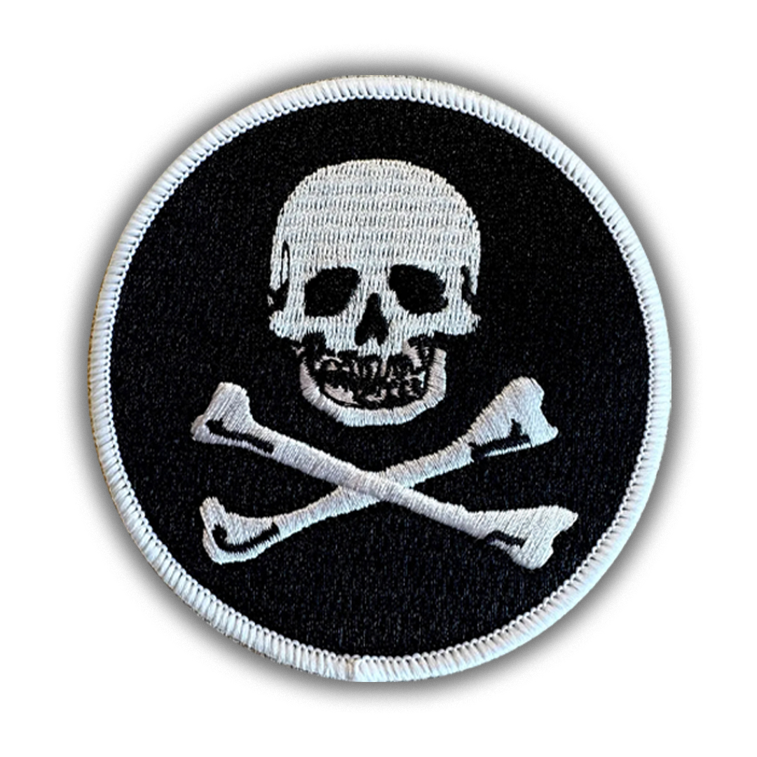 Round black morale patch with white embroidered Jolly Roger skull and crossbones design and a clean merrowed border.